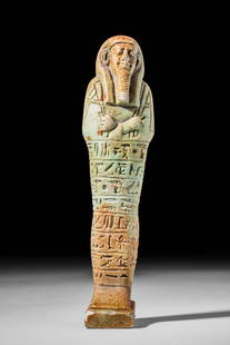 EGYPTIAN FAIENCE USHABTI OF UAHIBRA BORN OF ASETIRIDIES: Late Period, Ca. 664 - 332 BC.A mould-formed faience ushabti standing with fused legs atop an integral rectangular plinth and covered in a pale turquoise-hued glaze. The body gradually widens towards