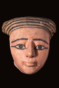 EGYPTIAN PAINTED MASK: 25th Dynasty, Ca. 750 - 650 BC. A carved wooden sarcophagus mask in cedar, covered with gesso and gilt. Idealised facial features with a long thin nose, pursed lips, wide almond-shaped eyes and