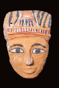 EGYPTIAN PAINTED MASK: Late Period, Ca. 664 - 332 BC. An intricately carved cedar wood sarcophagus mask coated in gesso and paint. The mask features idealised facial characteristics, including a large nose, pursed lips,