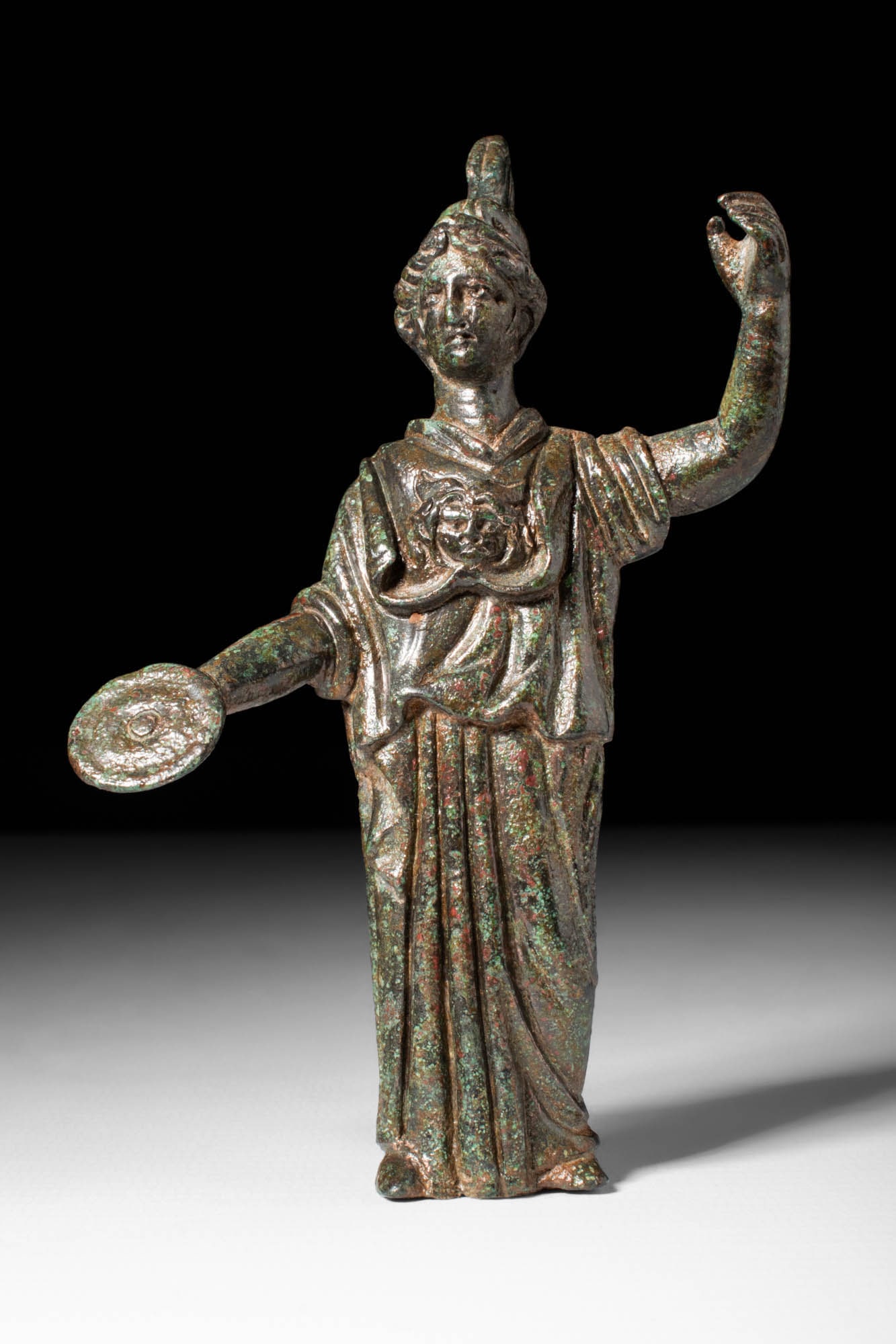 SUPERB ROMAN BRONZE STATUETTE OF MINERVA: Ca. AD 100 - 200 . A bronze statuette of Minerva captures her poised and dignified form in an elegant, detailed figure. She wears a crested helmet with intricate designs. Her robes, finely incised, dr