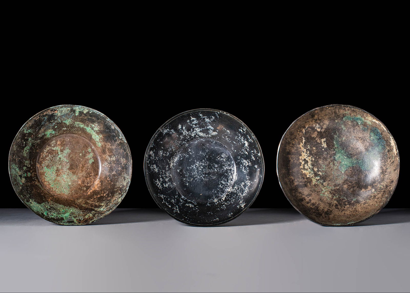 COLLECTION OF ETRUSCAN BOWLS: Ca. 600 - 400 BC. A collection of bowls. The first with a shallow design, diagonal rim, and flat foot. A concentric circle adorns the tondo, as is customary for Etruscan ware; the second is a bronze b