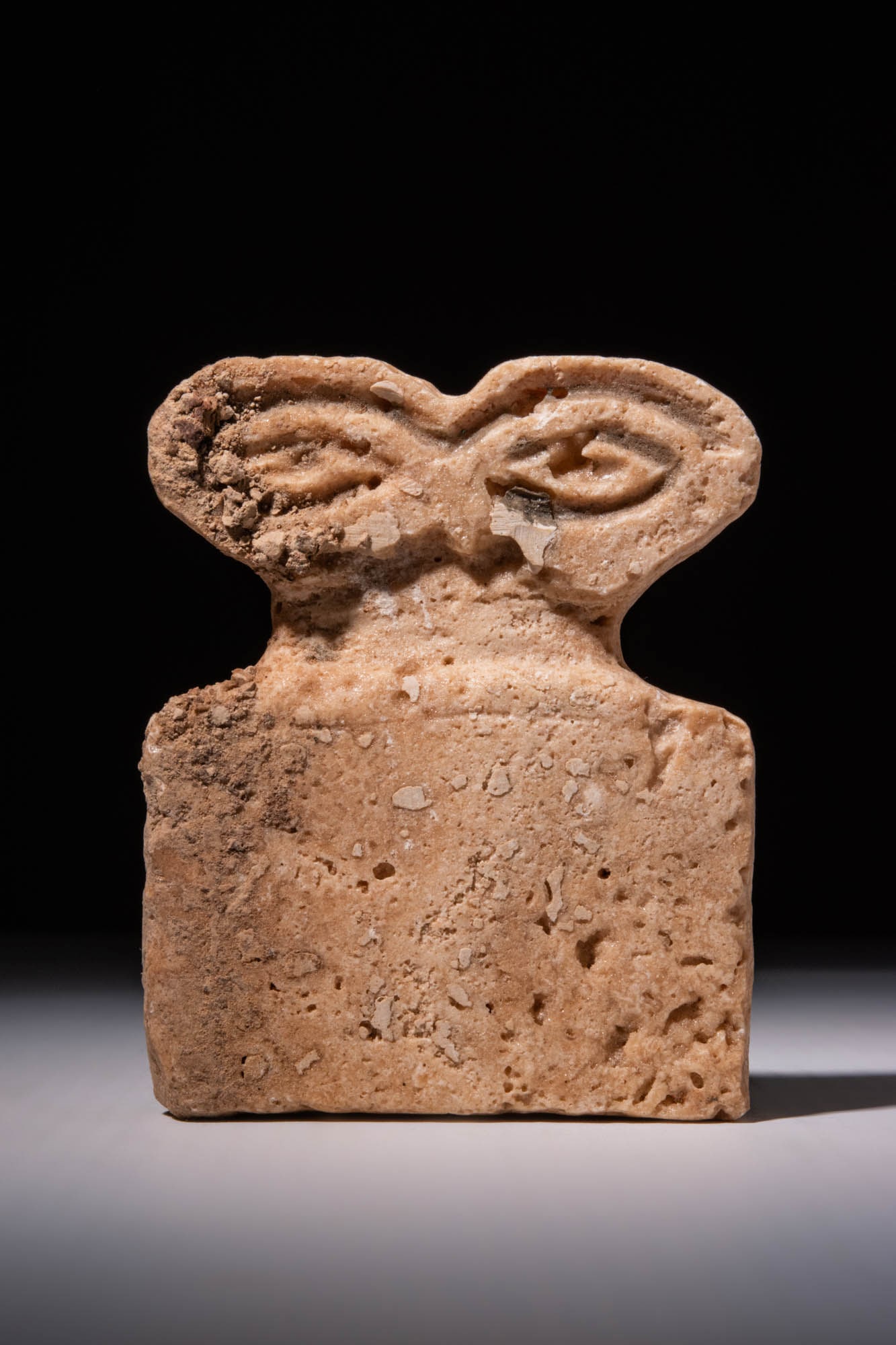 TELL BRACK STONE EYE IDOL: Ca. 3700 - 3500 BC. A stone eye idol featuring a rectangular body with a flat base and straight sides. The figure is topped with a pair of almond-shaped eyes with recessed pupils. The rear of the idol