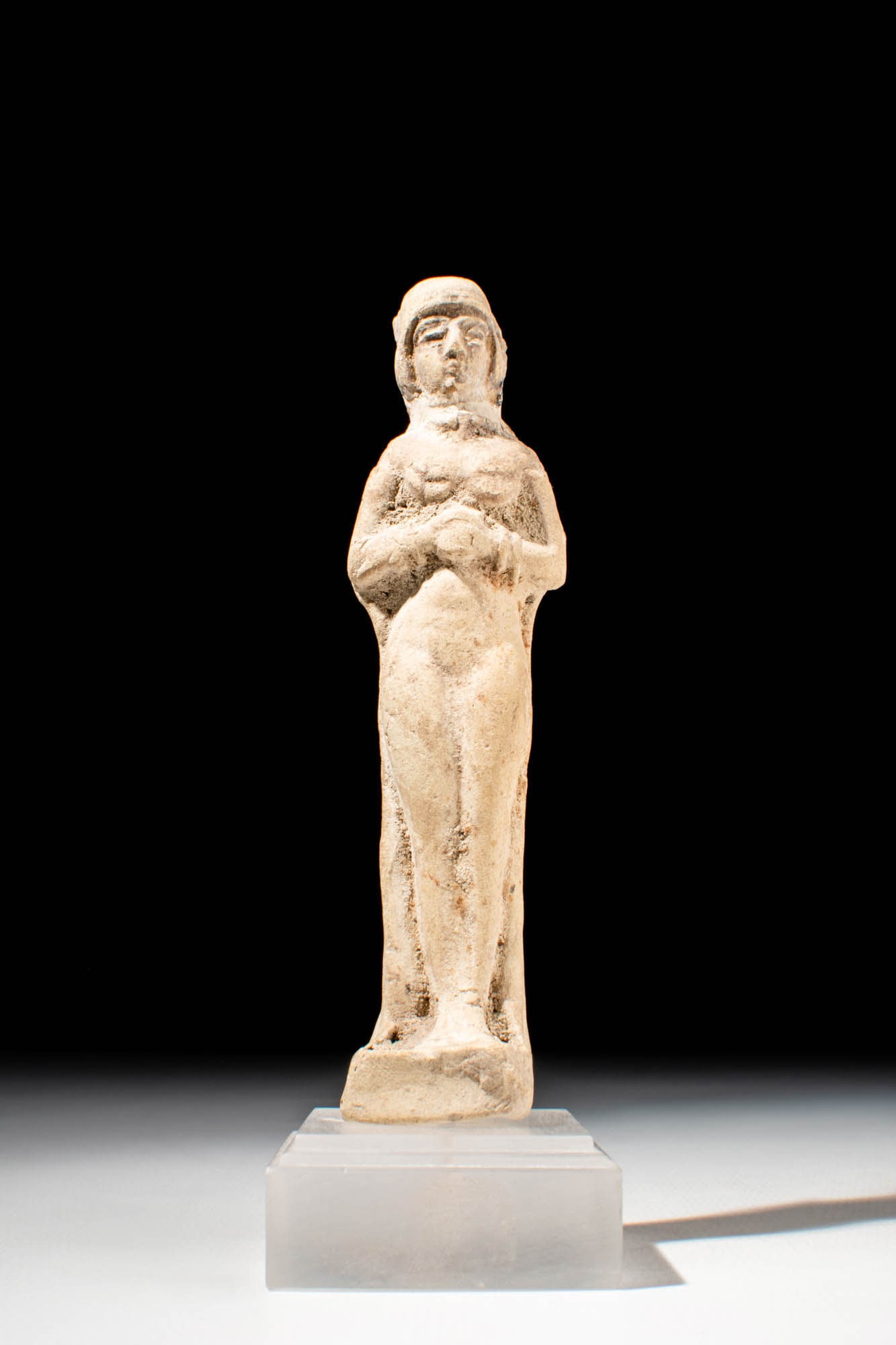 SUMERIAN STATUETTE OF GODDESS: Ca. 1400 - 800 BC. A terracotta statuette of a goddess depicted standing nude, with both hands held to the chest. The facial features are shallowly defined, with large eyes, a prominent nose, and a sm