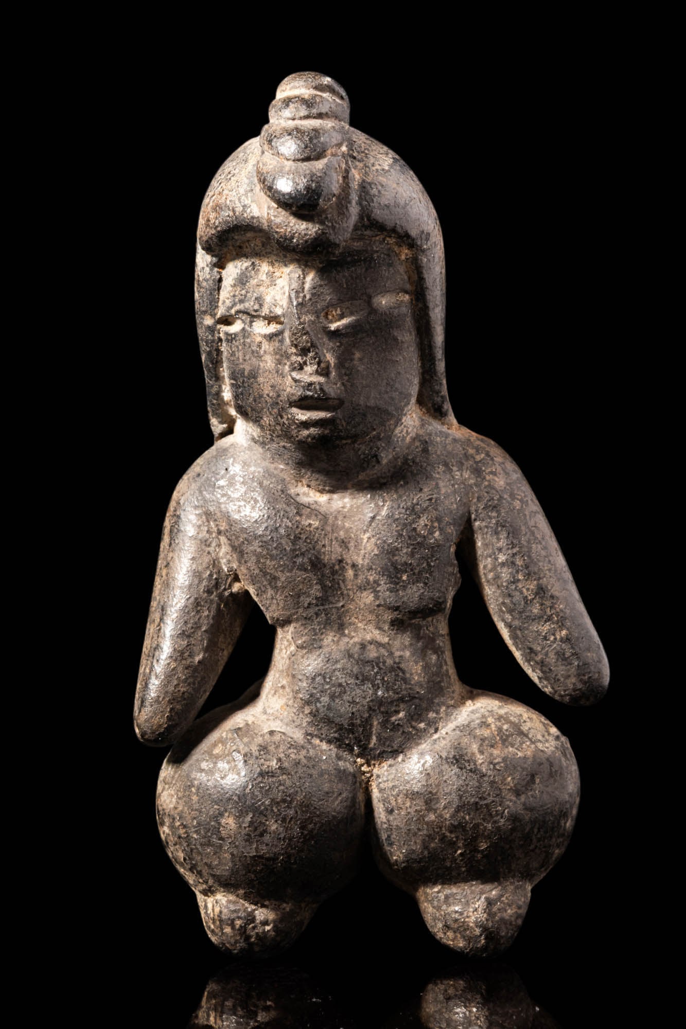 TLATILCO BLACK TERRACOTTA FEMALE FIGURE: Ca. 700 - 600 BC. A black terracotta seated female figure with exaggerated legs. Her head features a distinctive coiled hairstyle, with subtly defined facial features. The arms extend outward.For simi