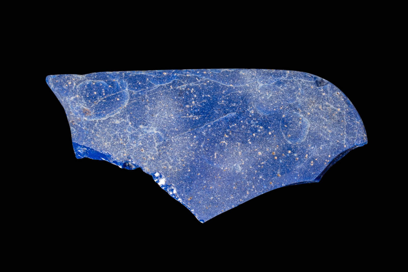 EGYPTIAN BLUE GLASS INLAY: Ca. 300 - 100 BC. A fragmentary glass inlay with a slightly curved profile. The surface exhibits a deep cobalt hue. Reviewed by Simone Musso, consultant curator for Egyptian antiquities at the Stibber