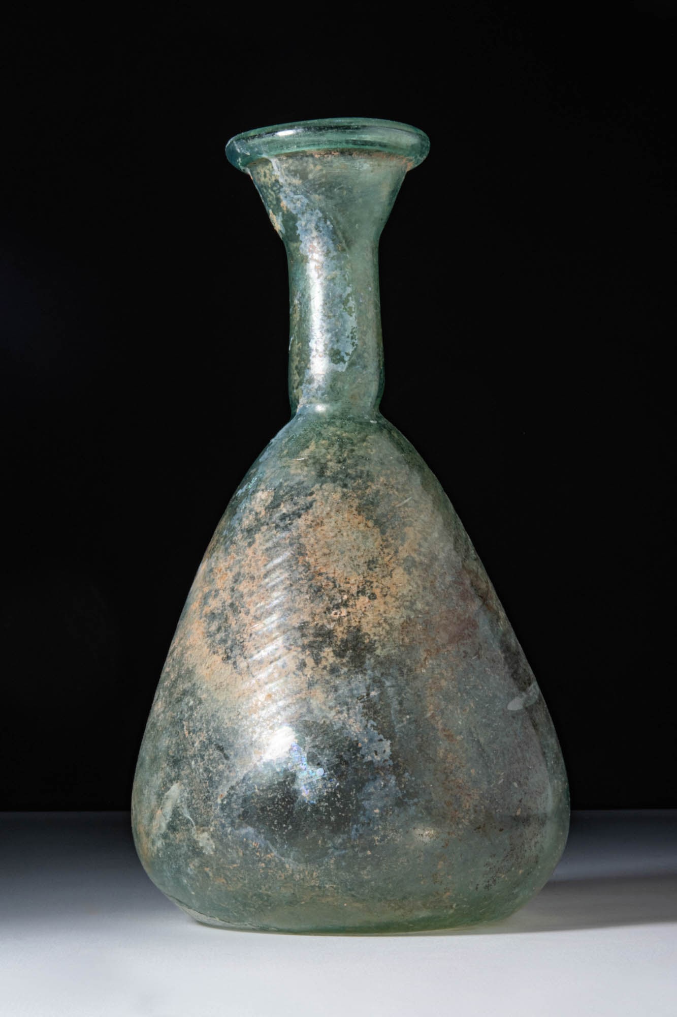 HUGE ROMAN GLASS PEAR SHAPE UNGUENTARIUM: Ca. AD 300. A translucent pale green glass unguentarium. Its pear-shaped body tapers towards a concave base and continues into a tall cylindrical neck with a flared, outward-folded rim.For similar see