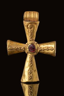 BYZANTINE GOLD CROSS PENDANT WITH CABOCHON: Ca. AD 900 - 1000. A gold cross pendant with hollow-formed flaring arms, each decorated with a raised beaded pattern running along the length. A circular setting at the centre holds a cabochon-cut gem