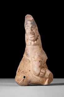 PRE-COLUMBIAN STONE FIGURINE: . A figure sculpted from pale stone, depicting a pot-bellied male with clearly defined facial features, including prominent cheeks, broad lips, and a wide nose. A tall, conical cap or headdress surmou