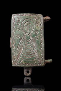 BYZANTINE BRONZE ENKOLPION WITH SAINT: Ca. AD 1000 - 1200. A bronze engraved enkolpion depicting a saint. He is wearing a long robe and a large cloak; the facial features are stylised, and the head is surrounded by an aureole. The main fig