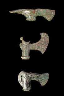 COLLECTION OF EARLY GREEK / BRONZE AGE AXE HEADS: Ca. 1200 - 900. A collection of three socketed bronze axe heads. The uppermost example is fitted with a vertical blade and a horizontal adze set on opposite sides of the socket. The central axe has a