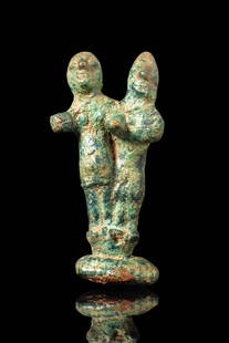 CANAANITE BRONZE GROUP OF FOUR DEITIES: Ca. 2nd Millennium BC. A cast bronze pair of figures depicting a male and female standing side by side on an integral rounded base. The female is modelled with prominent breasts and broad hips, while