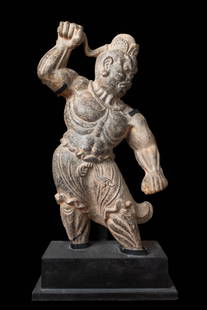 CHINESE STONE FIGURE OF A GUARDIAN: Tang Dynasty, Ca. AD 618 - 907. A guardian figure finely sculpted in stone with a dynamic posture, mid-stride, with one arm raised and the other clenched in a fist. Carved with a muscular torso, while