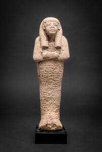 SUPERB EGYPTIAN CERAMIC USHABTI OF THE INFANTRYMAN KHAIY: New Kingdom, Ca. 1550 - 1069 BC. A ceramic ushabti with a tripartite wig and crossed arms holding agricultural implements. The face is rounded, with defined lips and prominent eyes. The mummiform body