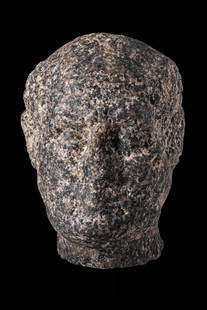 RARE EGYPTIAN GRANITE HEAD OF A MALE VOTARY: Ptolemaic Period, Ca. 200 - 30 BC. A head carved from granodiorite, representing a male votary with naturalistic facial features. The face is broad, with small, recessed eyes, a flattened nose, and a