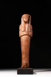 EGYPTIAN WOODEN USHABTI RAMESSIDE PERIOD: New Kingdom, Ca. 1292 - 1189 BC. A wooden ushabti with a tall, upright form and angular limbs. The elongated face is incised with defined eyes, nose, and mouth. The figure wears a tripartite wig, and