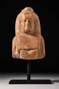 EGYPTIAN STONE BUST OF ISIS: Ptolemaic Period, Ca. 332 - 30 BC. A stone bust depicting a female figure identified as Isis. The figure is shown with a long tripartite wig. The face is rounded, with deep-set eyes, a prominent nose,