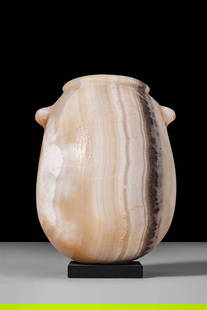 EGYPTIAN ALABASTER PEAR-SHAPED VASE: Late Period, Ca. 664 - 332 BC. A vessel carved from translucent banded alabaster with a globular, pear-shaped body terminating in an annular lip with a flattened, horizontal rim. Two small button hand