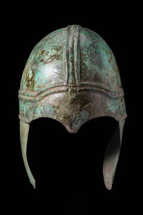 CHALCIDIAN BRONZE HELMET: Ca. 400 BC. A bronze helmet of Chalcidian type formed from a single sheet, composed of a rounded domed skull with a pair of broad raised ribs running longitudinally over the crown and intersected by t