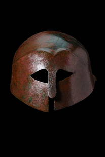 SUPERB BRONZE GREEK CORINTHIAN HELMET: Ca. 350 BC. A very fine bronze helmet of Corinthian type hammered from a single sheet, with a domed crown, almond-shaped eye cutouts, and a prominent nose guard. A shallow ridge forms two arched lines