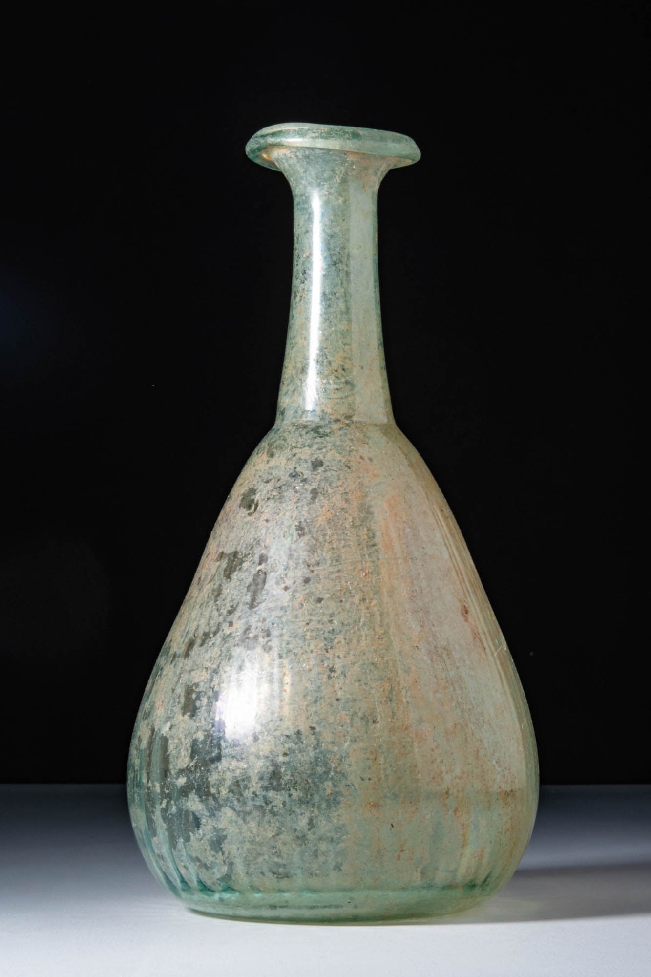 HUGE ROMAN GLASS PEAR-SHAPED UNGUENTARIUM: Ca. AD 1 - 200. A translucent pale green glass unguentarium. Its pear-shaped body tapers towards a concave base and continues into a tall cylindrical neck with a flared, outward-folded rim.For similar