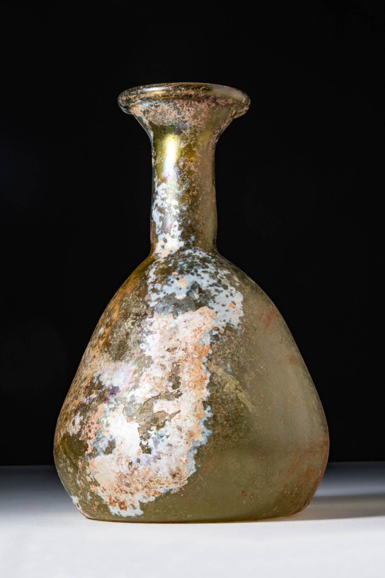 ROMAN GLASS PEAR-SHAPED UNGUENTARIUM: Ca. AD 1 - 200. A translucent yellowish glass unguentarium. Its pear-shaped body tapers towards a concave base and continues into a tall cylindrical neck with a flared, outward-folded rim.For similar