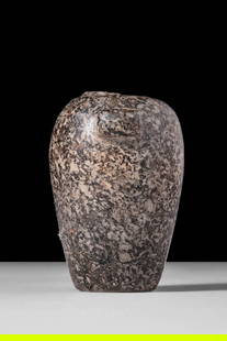 EGYPTIAN GRANITE VESSEL: Naqada II – Thinite Period, Ca. 3500 - 2900 BC. An ovoid vessel carved from dark grey granite with white and reddish inclusions. The body tapers towards the flat base. Two small protruding button ha