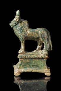 ROMAN BRONZE FIGURINE OF BULL ON PEDESTAL: Ca. AD 1 - 300. A solid-cast bronze figurine of a standing bull with a stocky body, slender legs, a prominent dewlap, and a hump over the shoulders. The head is crowned with short, upward-projecting h