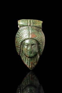 ROMAN BRONZE GODDESS APPLIQUÉ: Ca. AD 1 - 200. A cast bronze appliqué depicting the head of a goddess with centrally parted hair arranged in thick, textured waves beneath a broad headband. The face is oval with prominent cheekbone
