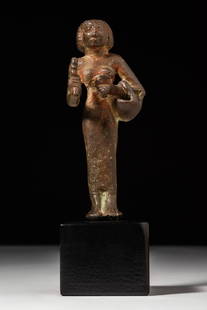 EGYPTIAN BRONZE PRIESTESS OF BASTET STATUE: 22nd Dynasty, Ca. 943 - 720 BC. A leaded bronze figurine of a priestess depicted standing and holding a sistrum in her right hand and an aegis with a basket in the crook of her left arm. She wears a l