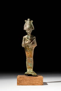 EGYPTIAN BRONZE PHARAOH AS OSIRIS: Ca. 664 - 332 BC. A bronze figure of a pharaoh represented as Osiris, standing mummiform with arms crossed, holding the crook and flail. The figure wears the atef crown with uraeus and flanking plumes