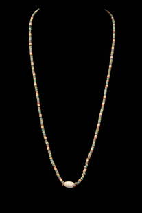 EGYPTIAN FAIENCE NECKLACE WITH CENTRAL STONE BEAD: Late Period, Ca. 664 - 30 BC. A restrung necklace with an assortment of multicoloured faience annular beads. The central section features a large, tubular-shaped stone bead serving as a pendant. Revie