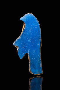 EGYPTIAN HIGH KARAT GOLD AND GLASS PENDANT DEPICTING A BIRD: New Kingdom, Ca. 1550 - 1069 BC. A gold and blue glass pendant in the form of a stylised bird. The pendant is crafted from a single piece of blue glass, shaped with a curved beak and an elongated body