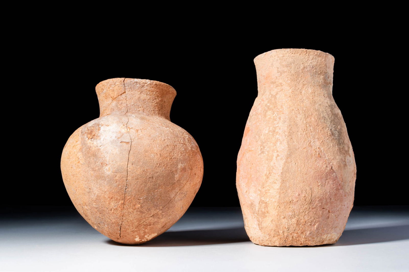 PAIR OF CYPRIOT BRONZE AGE VESSELS: Ca. 2000 - 1000 BC. A pair of pottery vessels. The first on the left has a bulbous body tapering to a pointed base, with a short neck and a rounded rim. The second has a tall body with a neck flaring