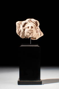 HELLENISTIC TERRACOTTA HEAD OF A MALE: Ca. 300 - 100 BC. A terracotta head of a male with wavy hair swept back from the forehead and falling in thick locks over the ears. The facial features are faintly defined, with circular eyes, a broad