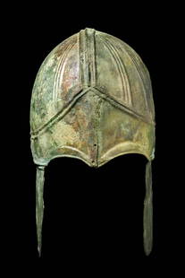 GREEK CHALCIDIAN BRONZE HELMET WITH CHEECKS: Ca. 500 - 400 BC. A Chalcidian bronze helmet, dating to the late 5th or early 4th century BC, finely crafted from a single sheet and distinguished by its segmented domed crown articulated by raised ri