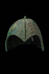 SCYTHIAN BRONZE HELMET - 'KUBAN' TYPE: Ca. 600 BC.A bronze helmet of the Kuban type, crafted as a single-piece structure. The helmet is characterised by its domed form and flared neck guard. The front of the helmet features distinct cutout