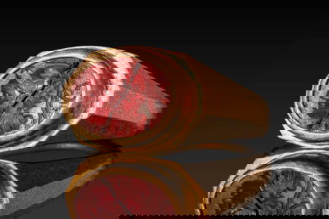 LATE ROMAN JASPER INTAGLIO DEPICTING MINERVA IN HIGH KARAT GOLD RING: Ca. AD 200 - 300. An oval garnet intaglio engraved with the profile bust of Minerva, facing left, wearing a crested helmet. The stone is set within a flat, circular bezel of a possibly later ring with