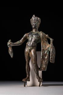 ROMAN BRONZE STATUETTE OF STANDING MERCURY: Ca. AD 1 - 200. A cast bronze figurine depicting the god Mercury standing with weight on the right leg. The right arm is extended forward, holding a money bag. The left arm is relaxed with a mantle dr