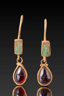 PAIR OF ROMAN HIGH KARAT GOLD EARRINGS WITH RED GARNET CABOCHONS AND EMERALDS: Ca. AD 300 - 500. A matched pair of gold earrings, each consisting of a rectangular emerald set in a box-like bezel linked to a teardrop-shaped garnet cabochon mounted in a smooth gold frame. The