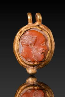 ROMAN HIGH KARAT GOLD PENDANT WITH PHILOSOPHER CARNELIAN CAMEO: Ca. AD 1 - 300. A carnelian cameo carved in high relief with the bust of a bearded PHILOSOPHER facing right. He is depicted with a bald crown, prominent brow, and neatly combed hair swept back above