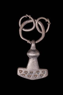 VIKING SILVER THOR'S HAMMER PENDANT: Ca. AD 900 - 1100. A silver pendant in the form of Thor&#8217;s hammer (Mj&#246;lnir), with a broad, flaring head and narrowed neck beneath a pronounced ridge. The lower portion is decorated with two