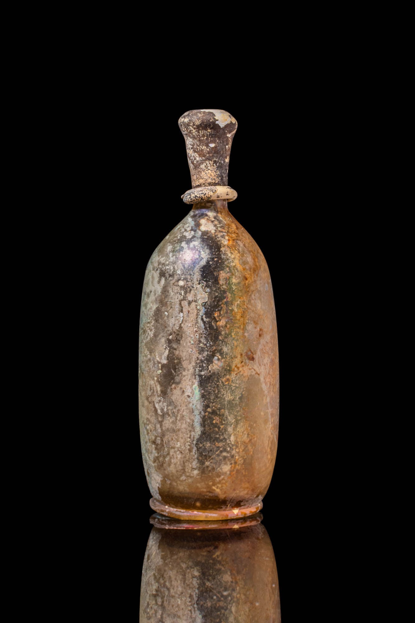 UMAYYAD GLASS BOTTLE: Ca. AD 750 - 900. A glass bottle with an elongated body and a funnel-shaped neck, ending in a pronounced rim. An applied ring encircles the base of the neck, and the body gently broadens towards a sli