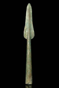 BRONZE AGE LONG BRONZE SPEARHEAD: Ca. 1800 - 1200 BC. A European cast in a fine greenish bronze spearhead with a narrow blade and pronounced midrib tapering to a sharp point, the shoulders subtly flared, the socket long and conical wi