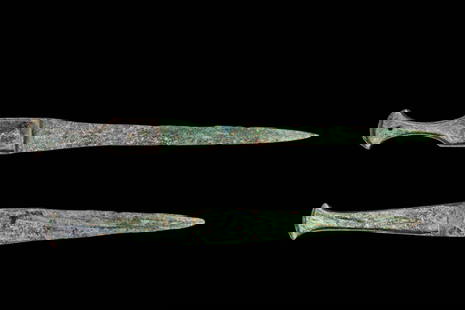PAIR OF EARLY GREEK / WESTERN ASIATIC BRONZE DAGGERS: Ca. 1200 - 800 BC. A pair of bronze daggers. The first one on top features a slender, tapering blade with straight edges converging to a sharp point. The hilt is composed of a flared, T-shaped pommel