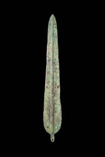 EARLY GREEK / WESTERN ASIATIC BRONZE SPEARHEAD: Ca. 1200 - 800 BC. A leaf-shaped bronze spearhead with an elongated, tapering blade and a well-defined midrib. The blade expands into softly rounded shoulders with a short rivetted tang at midpoint. F