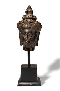KHMER BRONZE BUDDHA HEAD: Ca. 19-20th Century. A bronze head of Buddha finely cast with serene and symmetrical facial features, including almond-shaped eyes beneath arched brows, a broad nose, and full lips forming a subtle sm