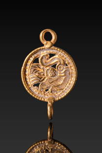 SCYTHIAN OPENWORK HIGH KARAT GOLD MEDALLION: Ca. 500 - 300 BC. A circular openwork gold medallion with a suspension loop above and an attachment ring below. The central field depicts a stylised bird in profile with a pronounced crest, curved