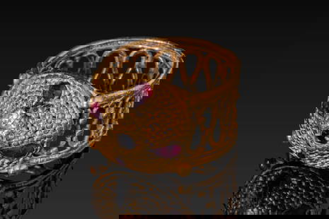 MEROVINGIAN OPENWORK HIGH KARAT GOLD RING WITH RED GARNET CABOCHONS: Ca. AD 800 - 1000. An openwork gold ring formed of a wide hoop formed of linked arches set between pronounced borders. The raised bezel is textured with dense filigree and set with four drop-shaped