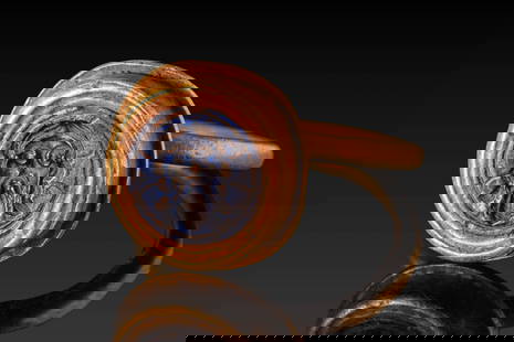 BYZANTINE HIGH KARAT GOLD RING WITH LAPIS LAZULI INTAGLIO DEPICTING CHRIST: Ca. AD 400 - 700. A blue lapis lazuli intaglio engraved with a frontal portrait of Christ with a beard, long hair, and nimbus, enclosed within a circular border. The bezel is set within a stepped,