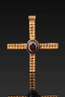 BYZANTINE HIGH KARAT GOLD CROSS PENDANT WITH BANDED AGATE CABOCHON: Ca. AD 600 - 800 . A gold cross pendant formed of four flat arms radiating from a central circular setting, composed of hammered sheet gold. The obverse is embellished with granulated-style punched